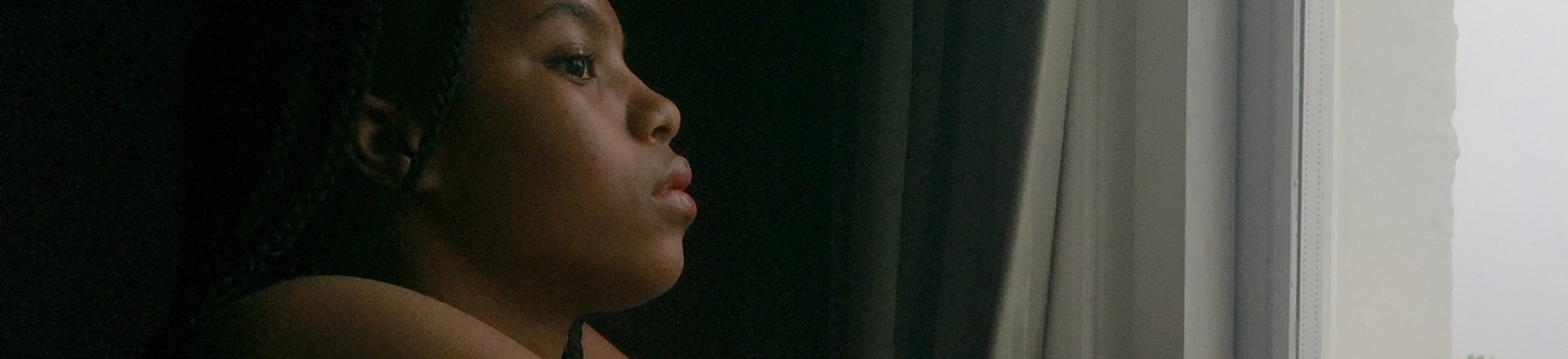 A photo of a woman staring out of her window.