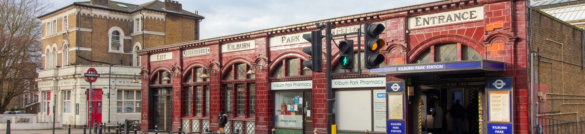 Red tiled tube station. Signs along the top of the building read (left to right):
Exit; Underground; Kilburn; Park; Underground; Entrance.