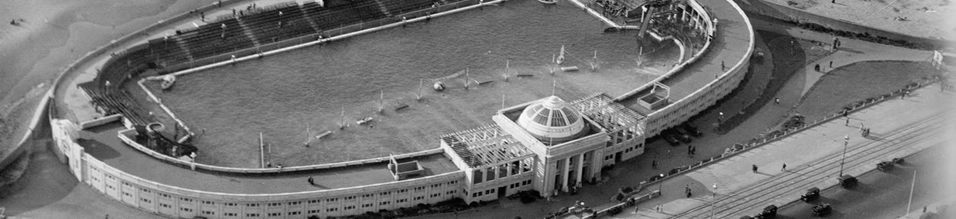 Aerial view of an open-air swimming pool set within an oval building