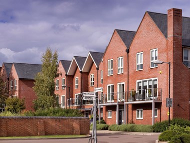 Modern three-storey brick housing with signage in the foreground.