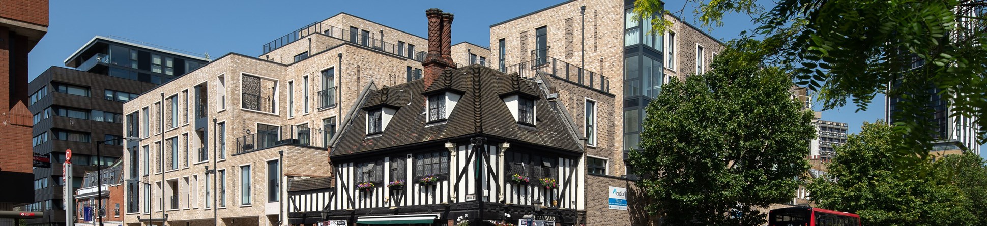 Black and white timber-framed building surrounded by modern housing blocks