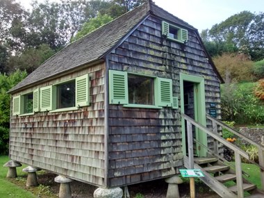 Photo of a small wooden shack with steps leading to its door. 