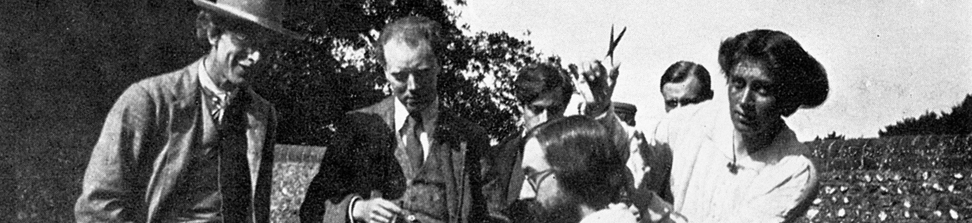 Vanessa Bell is cutting Lytton Strachey's hair while Roger Fry, Clive Bell, Duncan Grant and an unidentified guest look on