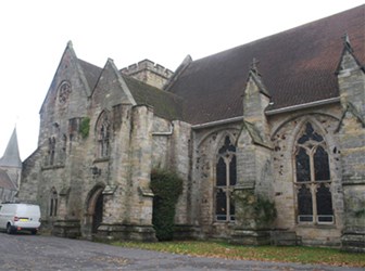 A large grey stone church building with buttresses and diamond-leaded windows