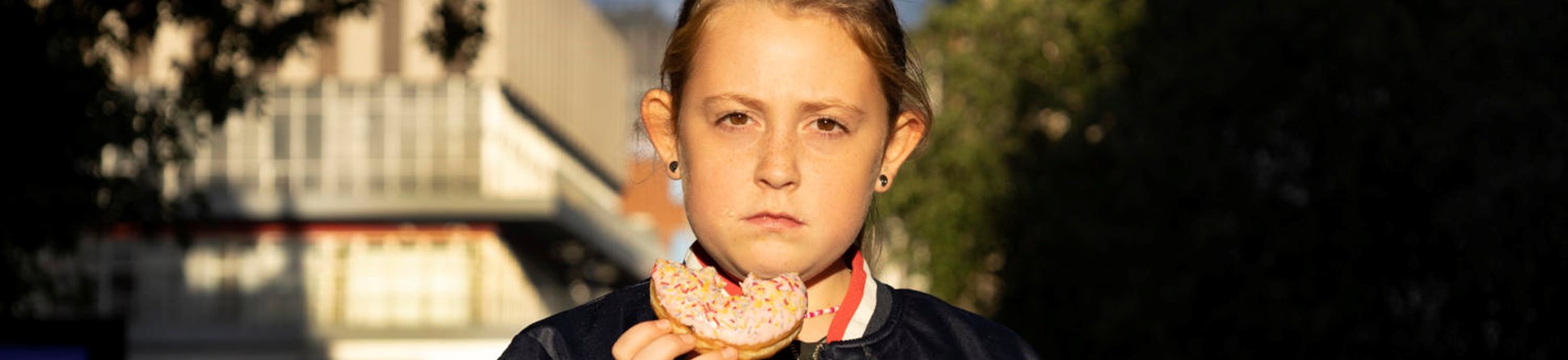 Portrait of a girl eating a donut on the street