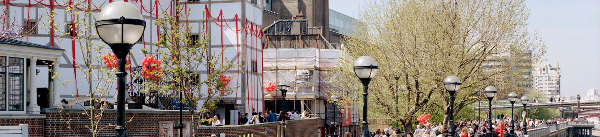 View along the riverside of crowds walking past Shakespeare's Globe theatre, London.