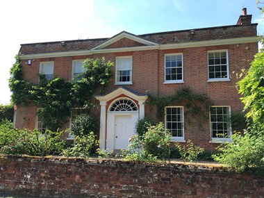 Image of the red brick house covered in climbing plants