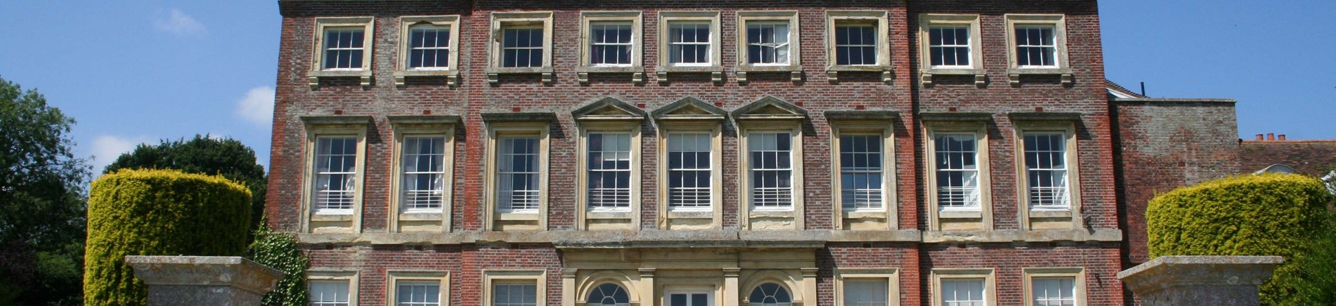 Image of Goodnestone Park house - a large red brick house with a blue sky behind