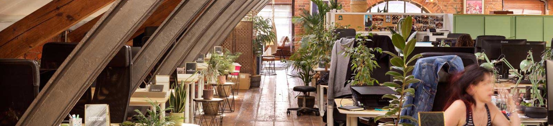 A view of an office within a historic mill building featuring arches of exposed girders.